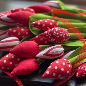Puede incluir: Un ramo de tulipanes de tela hechos a mano en rojo, blanco y verde. Los tulipanes tienen diferentes patrones, incluyendo lunares, rayas y hojas. Los tallos son verdes y el ramo est&aacute; atado con una cinta roja.