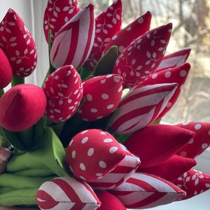 Puede incluir: Un ramo de tulipanes de tela roja con lunares blancos, rayas y patrones de hojas. Los tulipanes est&aacute;n dispuestos en un ramo y tienen un tallo verde.