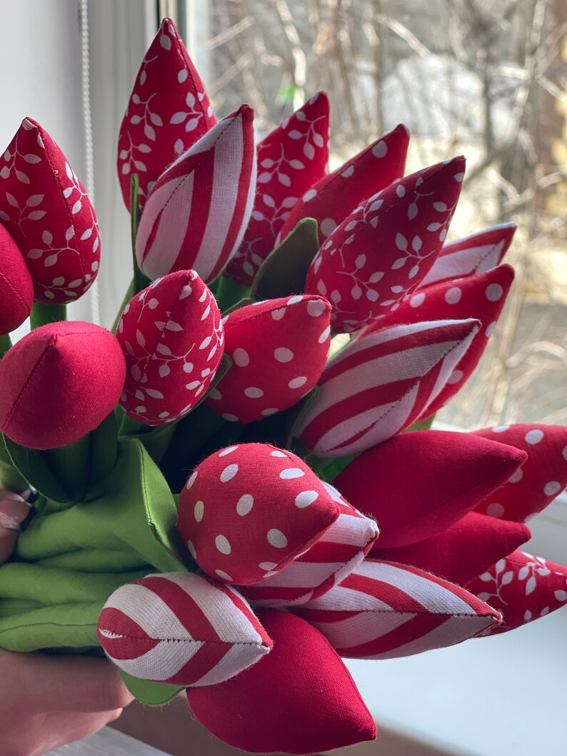 Puede incluir: Un ramo de tulipanes de tela roja con lunares blancos, rayas y patrones de hojas. Los tulipanes est&aacute;n dispuestos en un ramo y tienen un tallo verde.