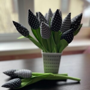 May include: A bouquet of black and white fabric tulips in a white and black polka dot vase. The tulips have different patterns, including polka dots, zigzags, and floral prints.