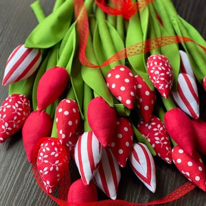 Puede incluir: Un ramo de tulipanes de tela roja con lunares blancos, rayas y patrones florales. Los tulipanes est&aacute;n atados con una cinta roja y tallos verdes.