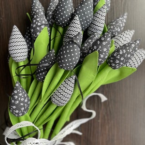 May include: A bouquet of black and white fabric tulips with green stems tied together with a white lace ribbon.