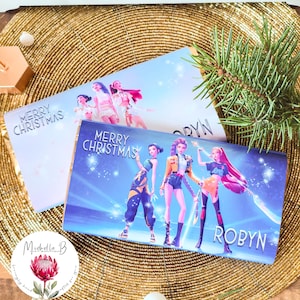 Könnte beinhalten: Zwei Weihnachtskarten mit blau-weißem Design. Die Karten zeigen eine Gruppe animierter Figuren und den Text "MERRY CHRISTMAS" und "ROBYN". Die Karten liegen auf einer goldfarbenen Perlenoberfläche.