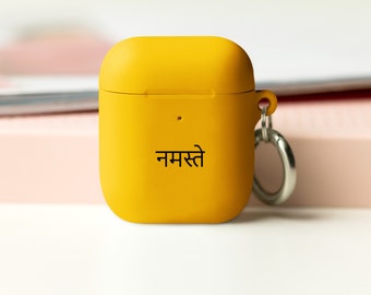 May include: A yellow silicone case for AirPods with a silver keychain and the word "Namaste" printed in black.