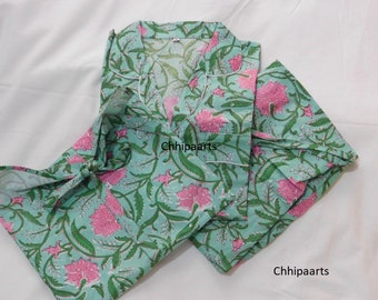 Op de afbeelding: Een pyjamaset met een bloemenprint in roze en groene tinten. De stof is lichtblauw met een witte rand om de kraag. De tekst "Chhipaarts" is zichtbaar op de stof.