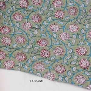 May include: Green fabric with a white and red floral pattern. The fabric has a blue outline around the flowers and leaves. The text "Chhipaarts" is printed on the fabric.