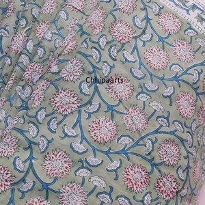 May include: Green fabric with a white and blue floral pattern. The fabric has a white border with a blue and white star pattern.