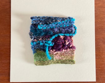 Woven textile art. Recycled fibres. Plant dyed fibres. Mounted size 10”x10”