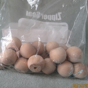 Peut inclure: Un sac en plastique rempli d'environ 20 perles rondes en bois naturel. Les perles sont toutes de la même taille et de couleur brun clair.