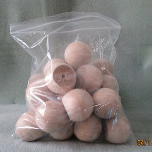 May include: A clear plastic bag filled with a large quantity of smooth, light brown wooden balls. The balls are approximately 2.5 cm in diameter.