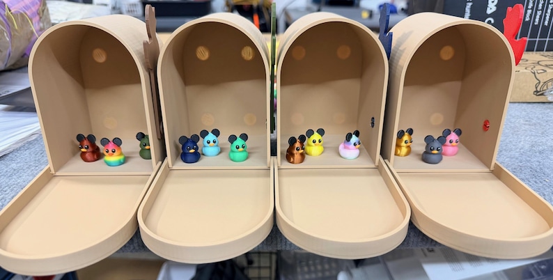 May include: Four beige mailboxes, each with a different assortment of colorful mouse figurines inside. The mice are various colors, including red, blue, yellow, and pink. The mailboxes have open trays and arched tops.