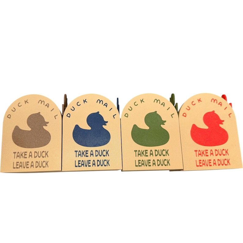 May include: Four duck-shaped cards in brown, blue, green, and red. Each card has the words "DUCK MAIL" and "TAKE A DUCK LEAVE A DUCK" printed on it. The cards are arranged in a row.