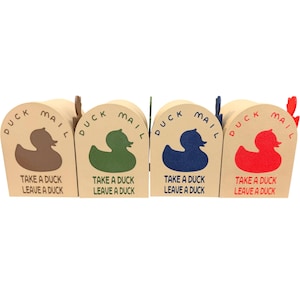 May include: Four small, beige cardboard mailboxes with arched tops. Each features a duck silhouette and the words "DUCK MAIL" and "TAKE A DUCK LEAVE A DUCK." The ducks are brown, green, blue, and red.