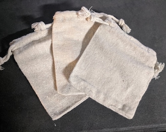 May include: Three small, off-white, drawstring fabric pouches made of a natural linen-like material.