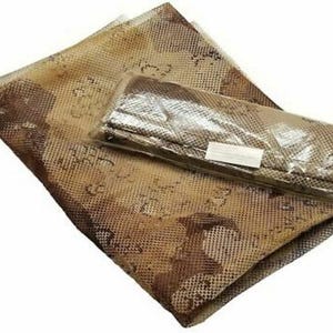 May include: A brown and beige mesh tablecloth with a pattern of small circles and a floral design. The tablecloth is folded and packaged in a clear plastic bag.