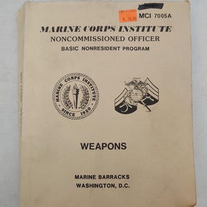 May include: A beige softcover training manual titled Marine Corps Institute Noncommissioned Officer Basic Nonresident Program Weapons. The cover features the Marine Corps Institute logo, a military insignia, and the text Marine Barracks Washington, D.C.