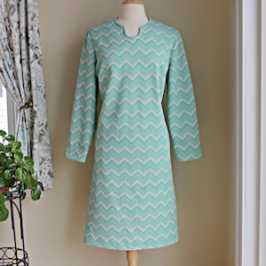 May include: A mint green dress with a white chevron pattern. The dress has long sleeves and a v-neck.
