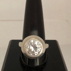 May include: A silver ring with a large, clear, round gemstone.