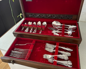 May include: A wooden box with a red velvet interior, containing a set of silverware. The box has a carved design on the top and a label that reads "Superplate".