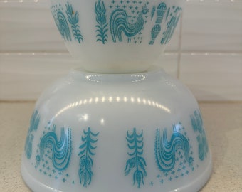 May include: Two white mixing bowls with a blue and white pattern of stylized roosters and wheat. The bowls are stacked on top of each other.
