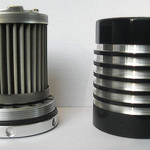 May include: Two silver oil filters, one with a black top and a black rubber ring, and the other with a silver top and a black rubber ring.