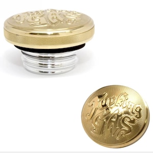 Puede incluir: Un tapón de depósito de metal dorado con un borde texturizado y el texto en relieve "Fucking GAS" en la superficie superior. El tapón incluye una base roscada plateada y una junta negra, mostrados de perfil y desde una vista superior.