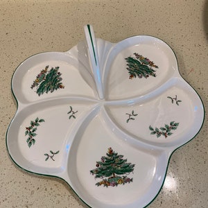 May include: A white ceramic serving dish with a green trim and a handle. The dish is divided into five sections, each featuring a Christmas tree design.