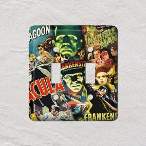 May include: A decorative light switch cover featuring a collage of vintage horror movie posters. The design includes images from "Dracula," "Frankenstein," and "The Invisible Man," with a distressed, aged appearance.