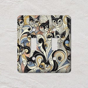 May include: A decorative triple light switch cover featuring a repeating pattern of stylized cats. The design incorporates black, cream, yellow, blue, and peach colors with swirling lines. The cover is square with three switch openings.