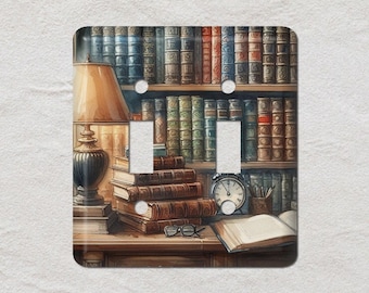May include: A decorative light switch cover with a watercolour illustration of a library scene. The design includes a lamp, books, an alarm clock, and glasses. The cover has two light switch openings.