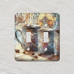 May include: Decorative light switch cover featuring three coffee mugs with ornate designs. The mugs are filled with coffee and sit on a wooden surface. Coffee beans are scattered around the mugs. The background includes a stained-glass window with a dove and cross.
