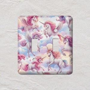 May include: A decorative light switch cover featuring a repeating pattern of unicorns with pink manes and tails, set against a pastel sky with clouds. The unicorns have golden horns and some have wings. The cover has two switch openings.