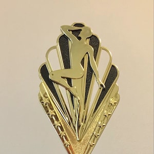 May include: Gold trophy with a purple base and a dancer silhouette on top. The base has a gold band around it and the words "YOUR WORDS HERE!" are on the base.