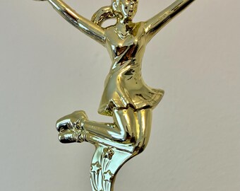 May include: A gold-colored trophy featuring a cheerleader in a dynamic pose, holding pom-poms aloft. The figure is on a decorative base, ideal for recognizing achievement in cheerleading or related activities.