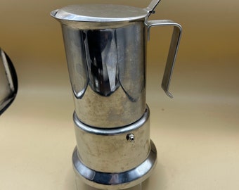 May include: A silver stainless steel stovetop espresso maker with a hinged lid and a handle.