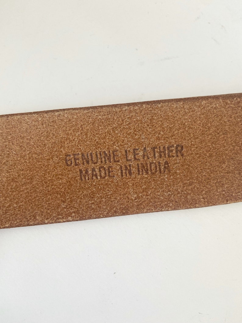 May include: Close-up of a brown leather belt with the text "GENUINE LEATHER MADE IN INDIA" embossed on the back.