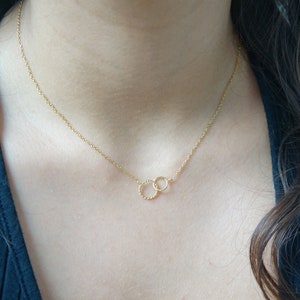 May include: A gold chain necklace with two interlocking circles as a pendant.