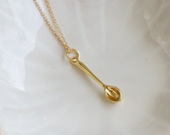 May include: A gold chain necklace with a small gold spoon pendant.