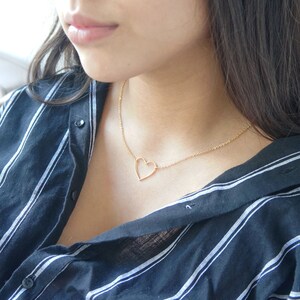 Puede incluir: Un collar de cadena dorada con un delicado colgante de coraz&oacute;n abierto.