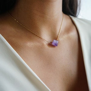 Puede incluir: Un delicado collar de cadena dorada con un peque&ntilde;o colgante de amatista facetado.
