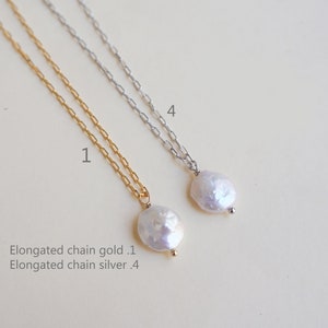 May include: Two delicate necklaces with elongated chains, one gold and one silver, each featuring a single white pearl pendant.