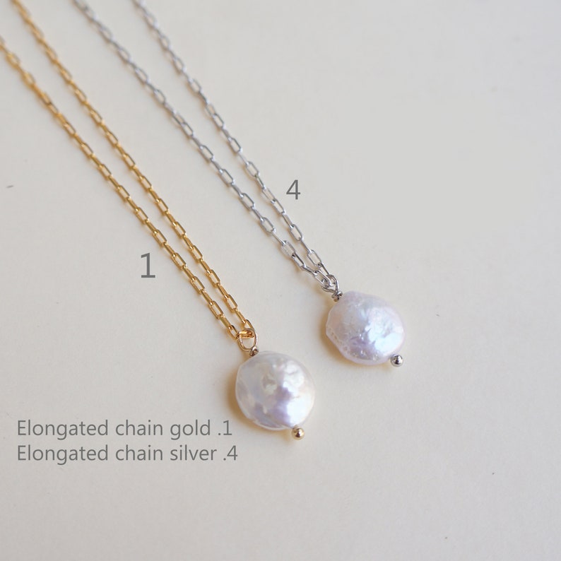 May include: Two delicate necklaces with elongated chains, one gold and one silver, each featuring a single white pearl pendant.