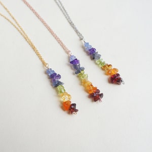 May include: Three necklaces with rainbow colored gemstone pendants. The necklaces are gold, rose gold, and silver.