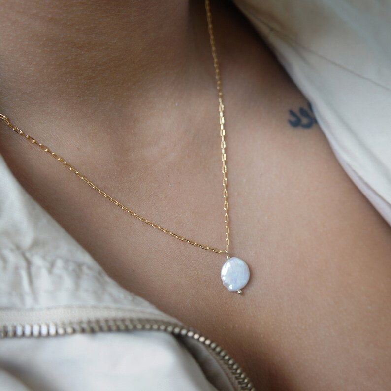 May include: A gold chain necklace with a single white pearl pendant.