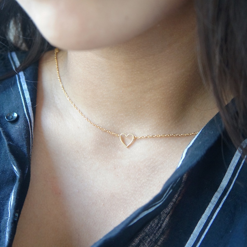 Puede incluir: Un collar de cadena de oro con un delicado colgante de coraz&oacute;n abierto.