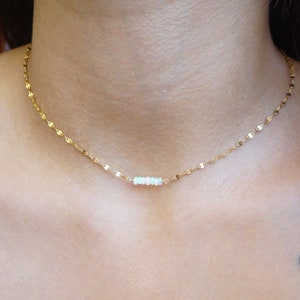 May include: A gold chain necklace with a small bar of opal stones.