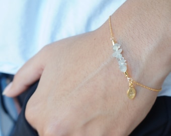 Könnte beinhalten: Ein goldenes Kettenarmband mit einem kleinen goldenen Anhänger und einem Cluster aus klaren Quarzkristallen.
