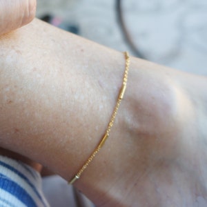 May include: A gold ankle bracelet with a delicate chain and small, round beads.