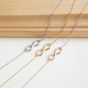 May include: Three infinity symbol necklaces in silver, gold, and rose gold. The necklaces are delicate and feature a simple infinity symbol charm.
