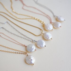 May include: A set of six necklaces with different chain styles, each featuring a white pearl pendant. The pearls are all different sizes and shapes, but they are all smooth and lustrous.